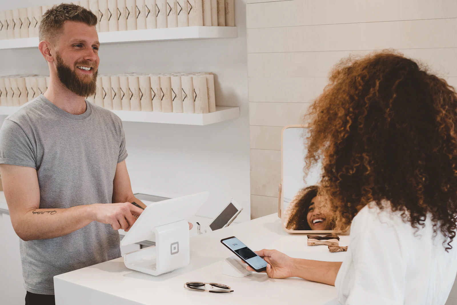Cliente pagando con el móvil en el mostrador de una tienda, ante el terminal de tarjeta